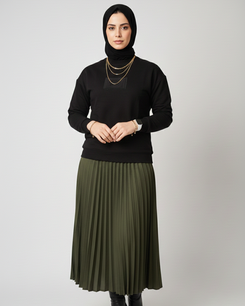 Woman wearing a black top and green pleated skirt on a white background
