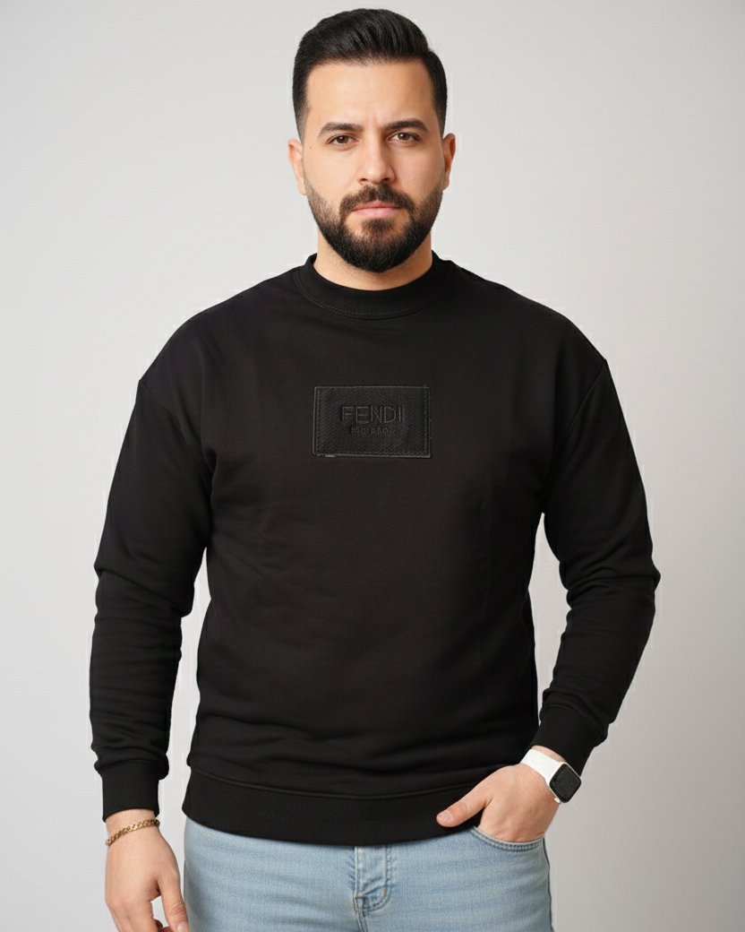 Man wearing a black sweater with a logo on a gray background