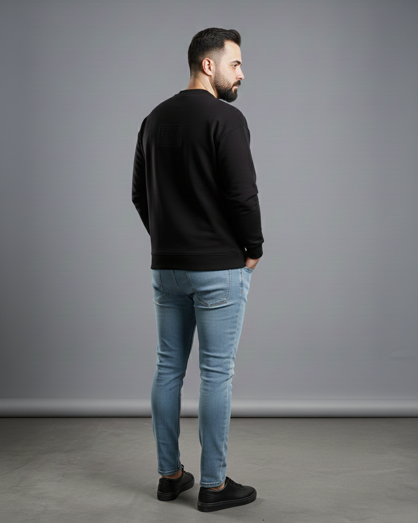 Man wearing a black sweater and light blue jeans standing against a gray background with 'Available on Shopify' text.
