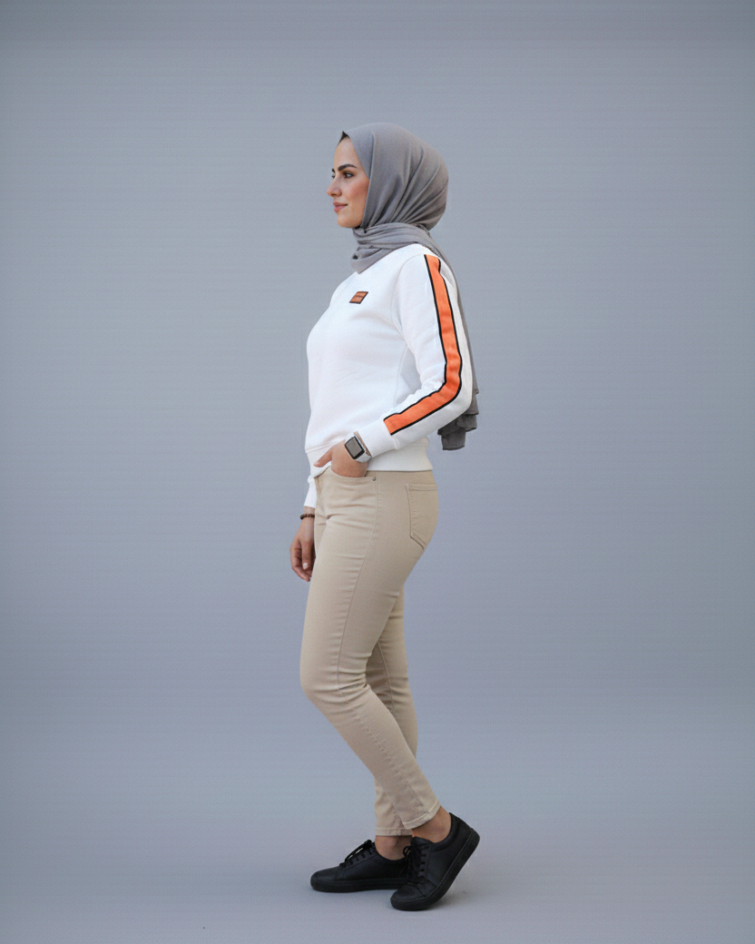 Woman wearing a white sweatshirt with orange stripes and beige pants on a gray background