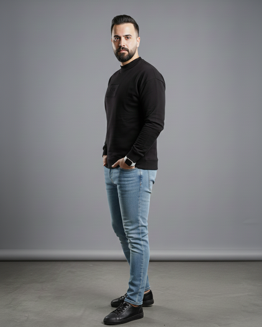 Man wearing a black sweater and blue jeans standing against a gray background with 'Available on Shopify' text.
